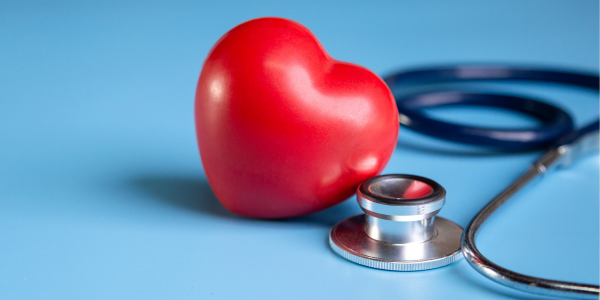 A red heart stress ball next to a stethoscope on a blue background