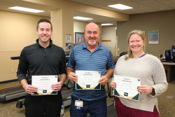 Three physical therapists holding awards