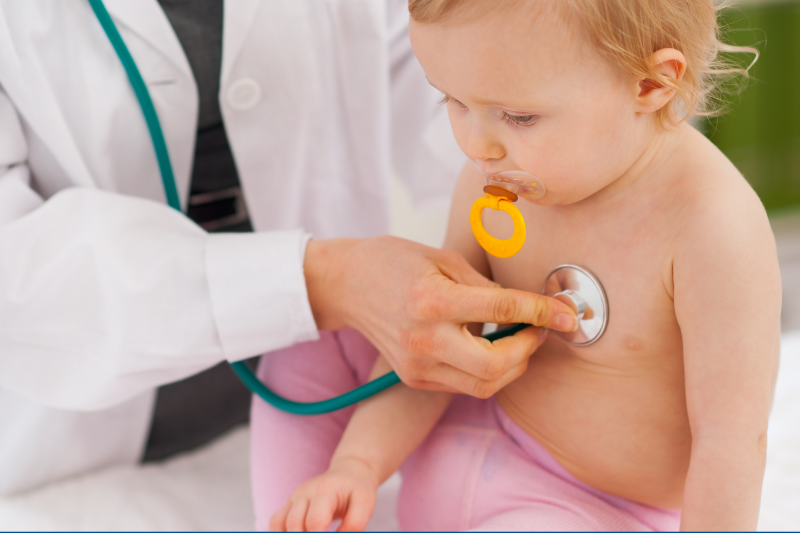A  baby wearing leggings and a doctor listening to the baby's heart
