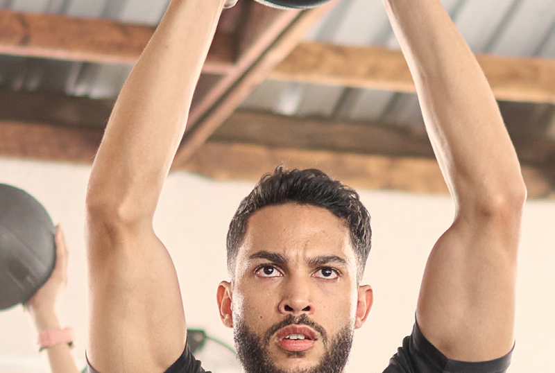 A man holding a medicine ball above his head