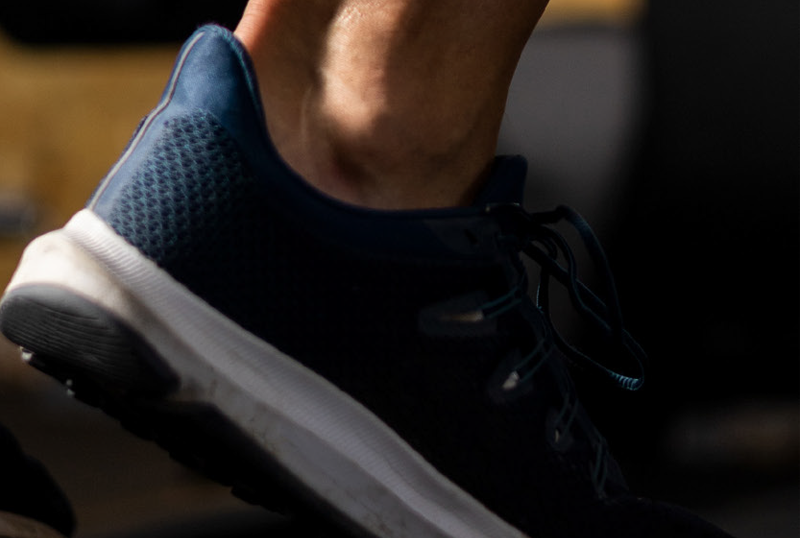 A person's foot wearing a blue low-cut tennis shoe