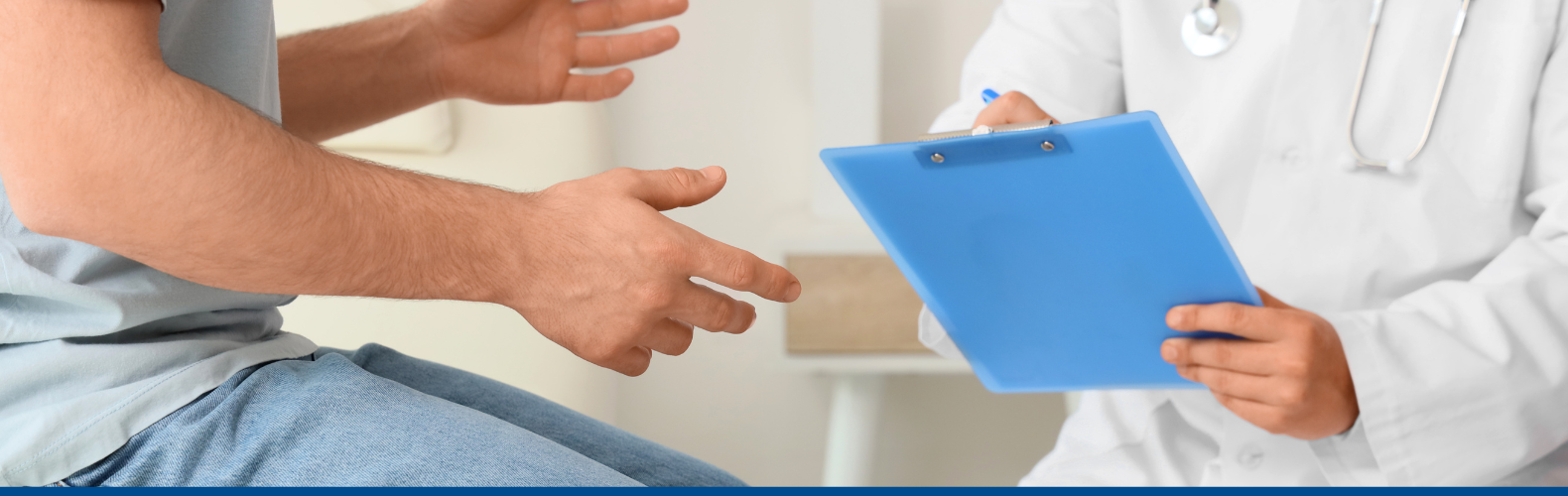 A man speaking with a doctor wearing a white coat and holding a blue clipboard